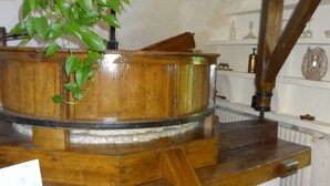 A wooden barrel with a plant hanging from it, placed on a wooden table with a gear mechanism underneath. - Charming cottage with pool, fountains, mill, park and plane trees (Apt)