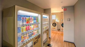 Un couloir avec des distributeurs automatiques et un lave-linge.