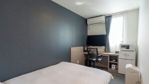Une chambre d’hôtel équipée d’un lit, d’un bureau avec une chaise, d’un four à micro-ondes, d’une machine à café et d’une télévision.
