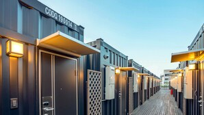 Une rangée de chambres d’hôtel, avec une terrasse en bois au premier plan et un ciel dégagé en arrière-plan.