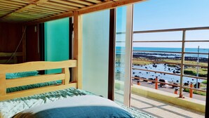 A wooden bed with a view of a rocky shoreline and water.