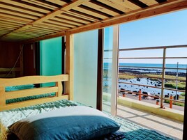 Una cama de madera con vistas a una costa rocosa y al agua.