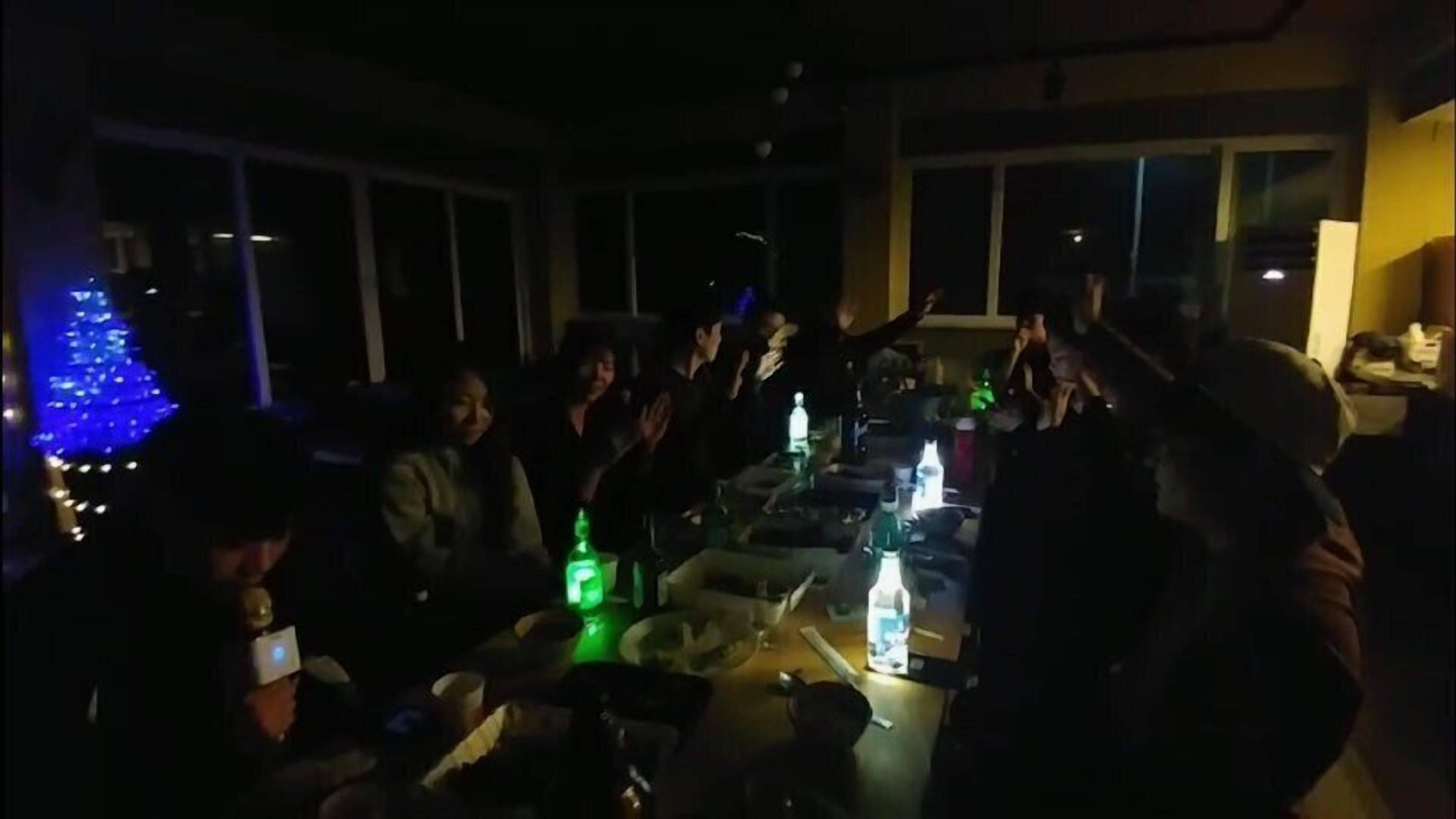 A dimly lit room with a group of people gathered around a table.