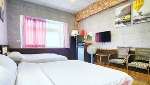 Camera d'albergo con un letto grande, una scrivania, una sedia, una televisione e una finestra con tende.