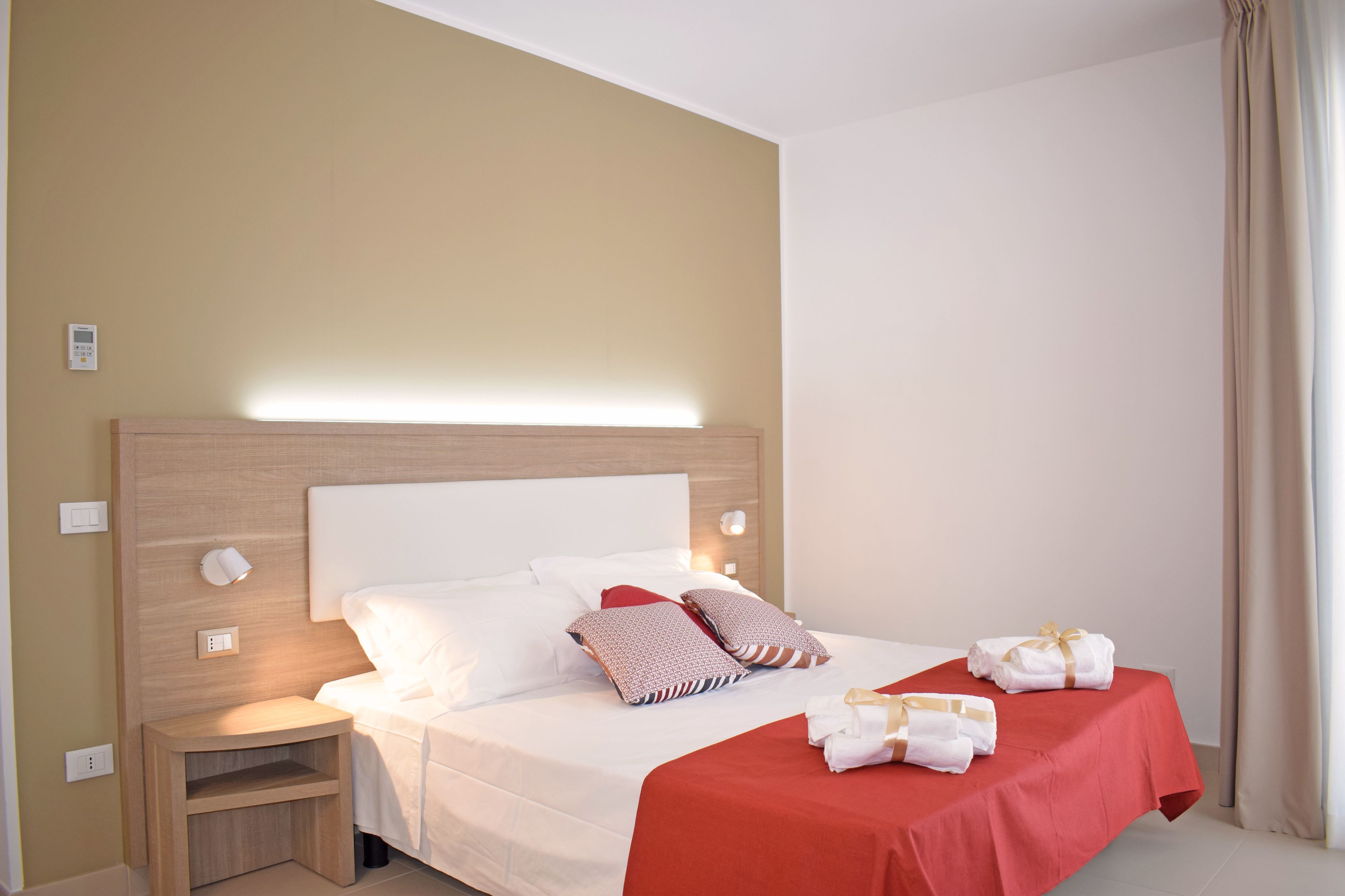 A hotel room with a bed, bedside table, and a nightstand.