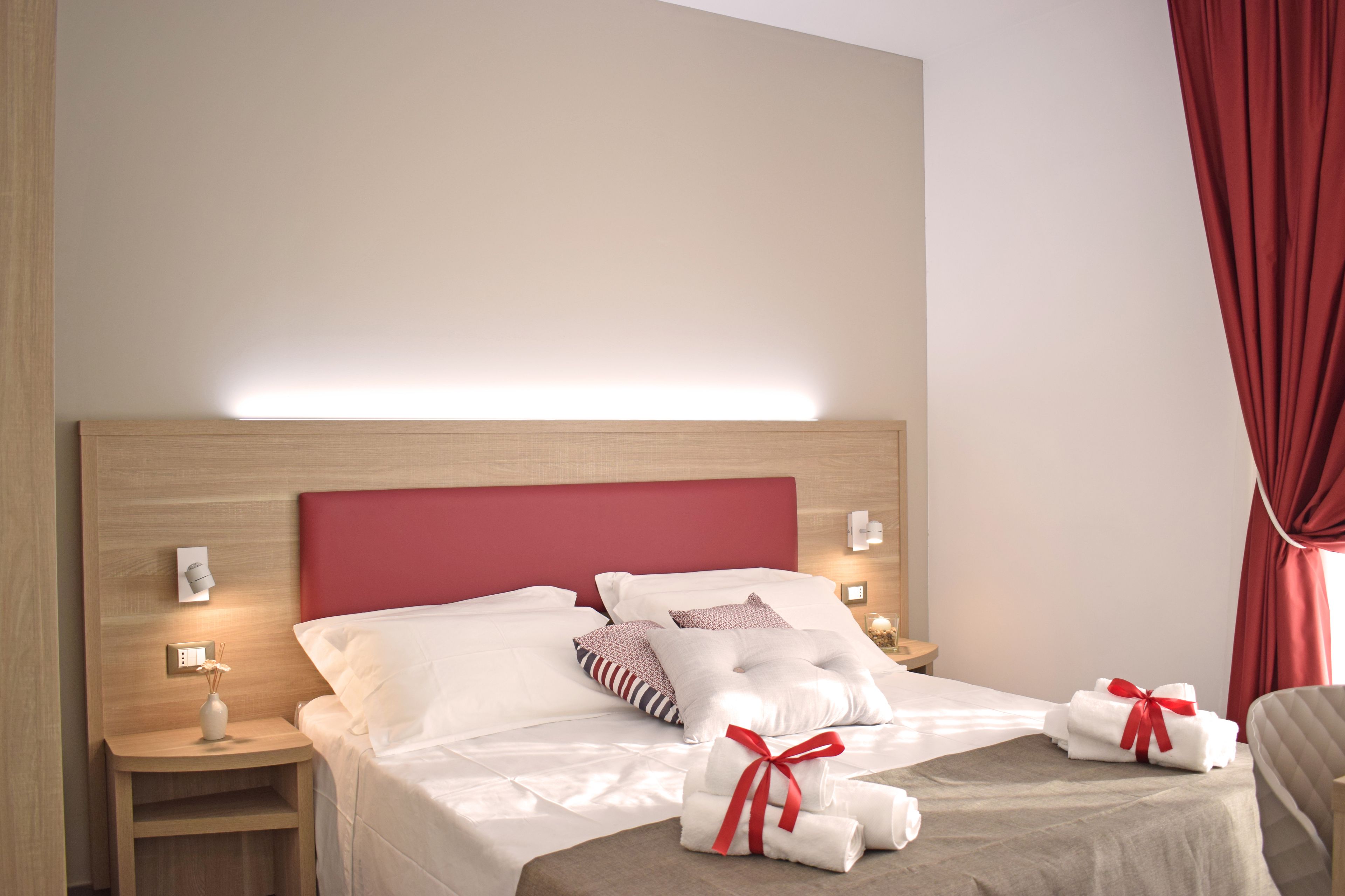 Una habitación de hotel con una cama, mesitas de noche y una mesilla.