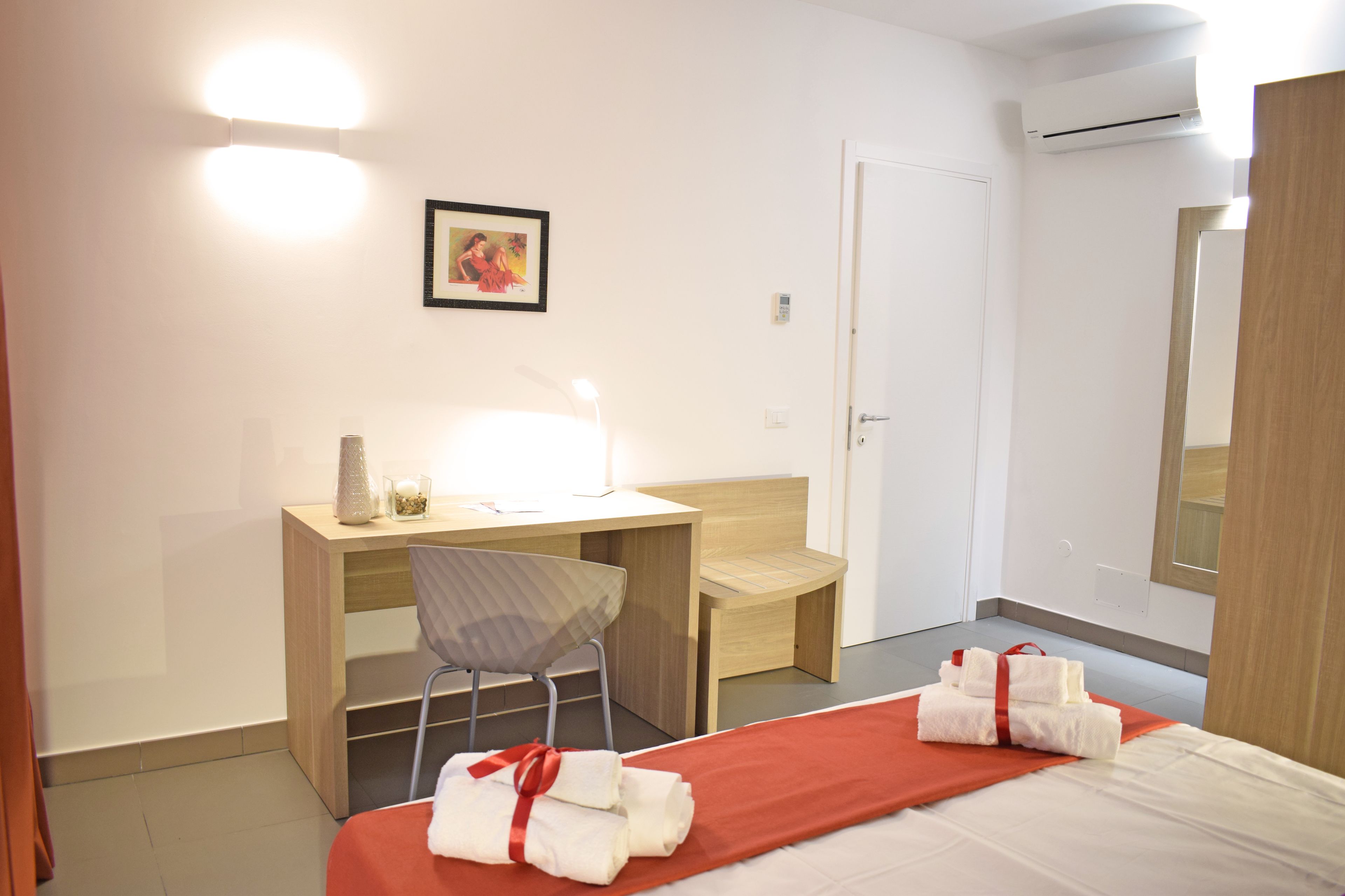 Una habitación de hotel con una cama, un escritorio, una silla y una mesita de noche.