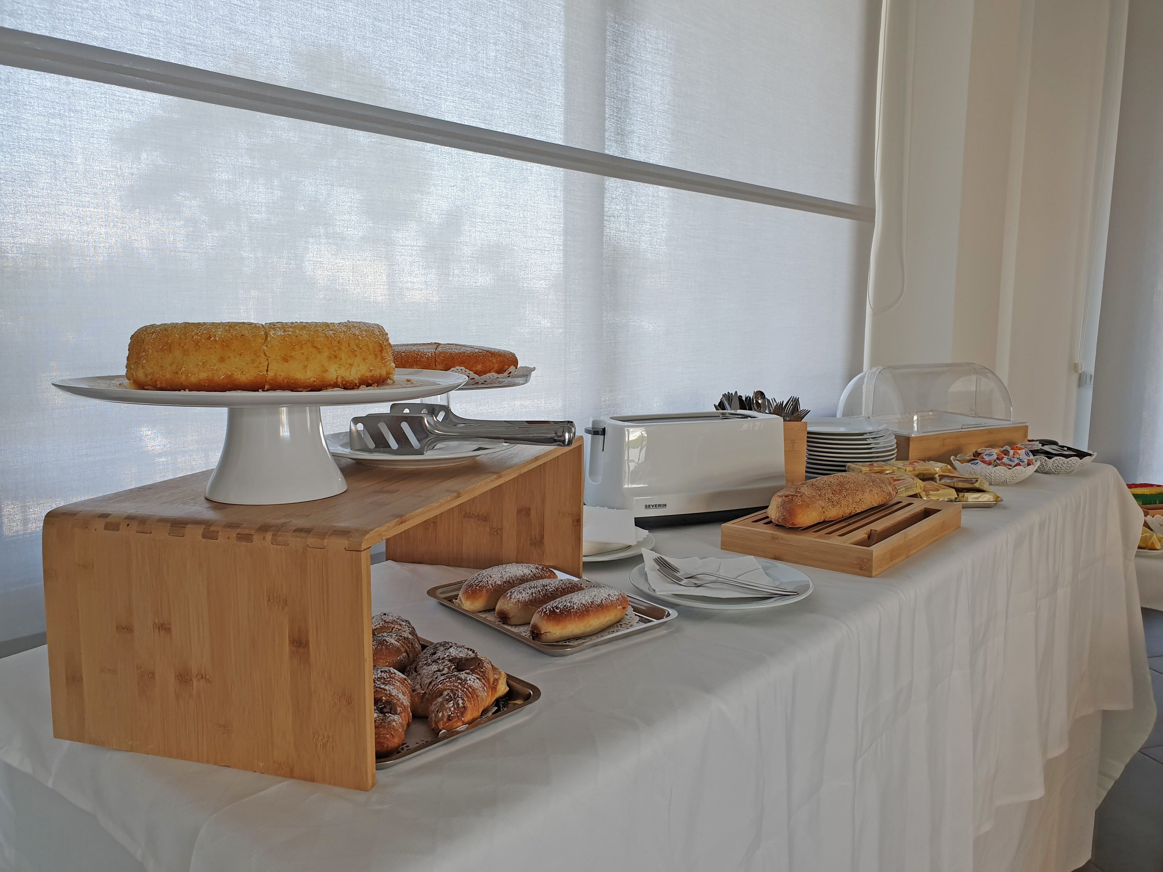 Una mesa de buffet con diversos productos horneados, como pan y pasteles, y un tostador.
