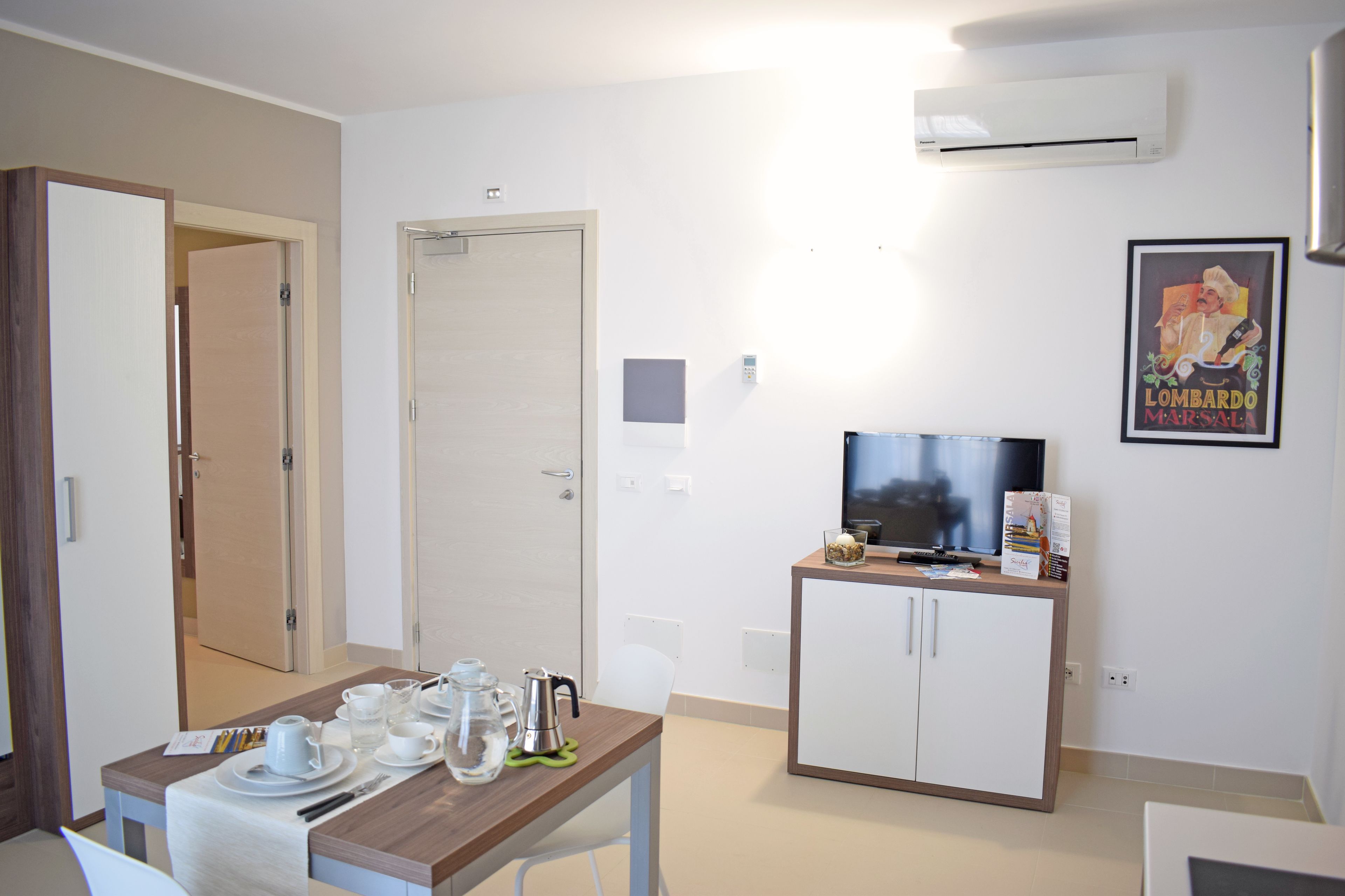 A hotel room with a dining area, a television, and a minibar.
