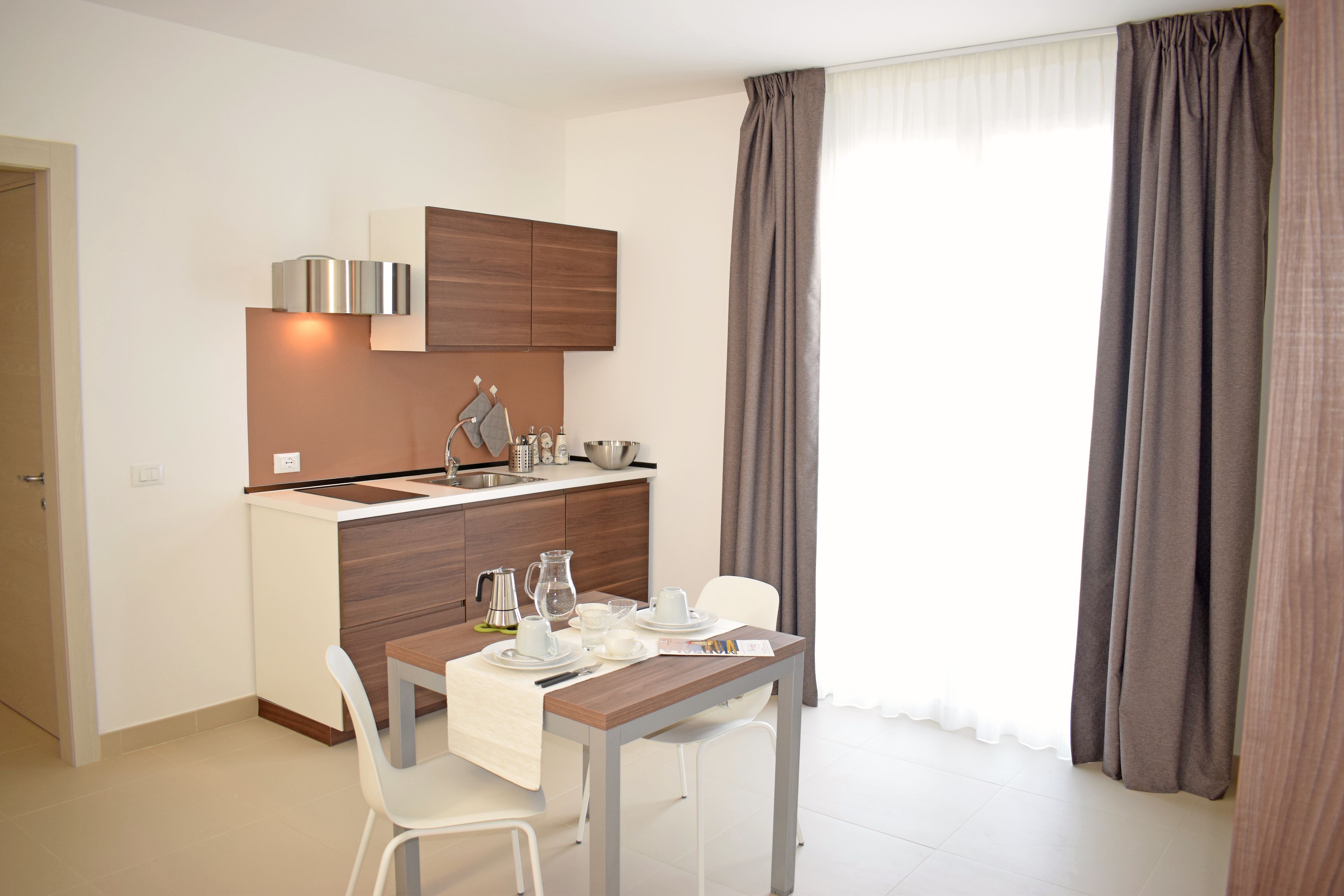 A modern kitchen with white cabinets, a wooden countertop, and a dining area with a table and chairs.