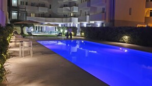 A modern building with a pool, outdoor seating, and well-lit balconies. - Travini Hotel Residence (Marsala)