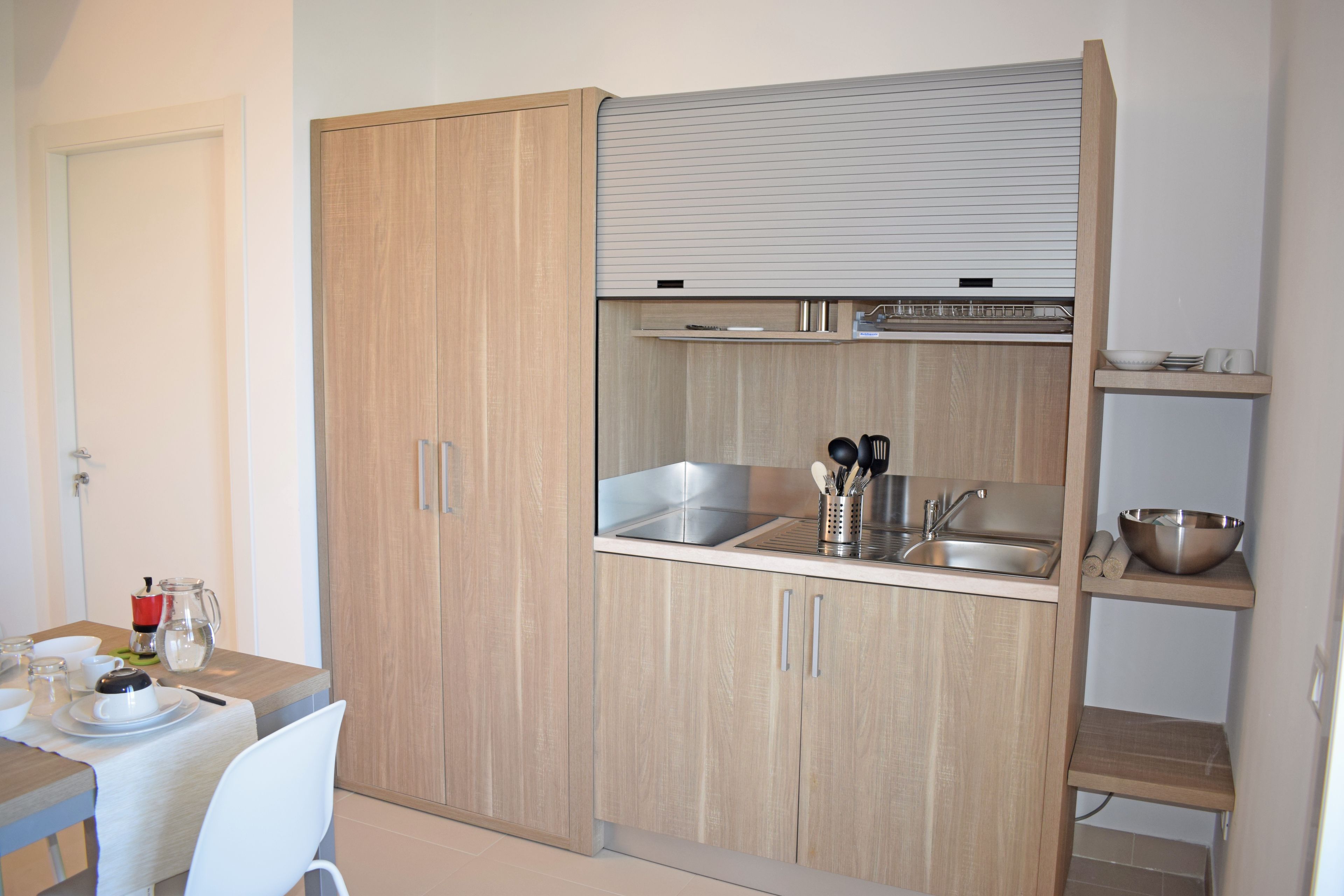 A compact kitchen with wooden cabinets, a sink, and a countertop.