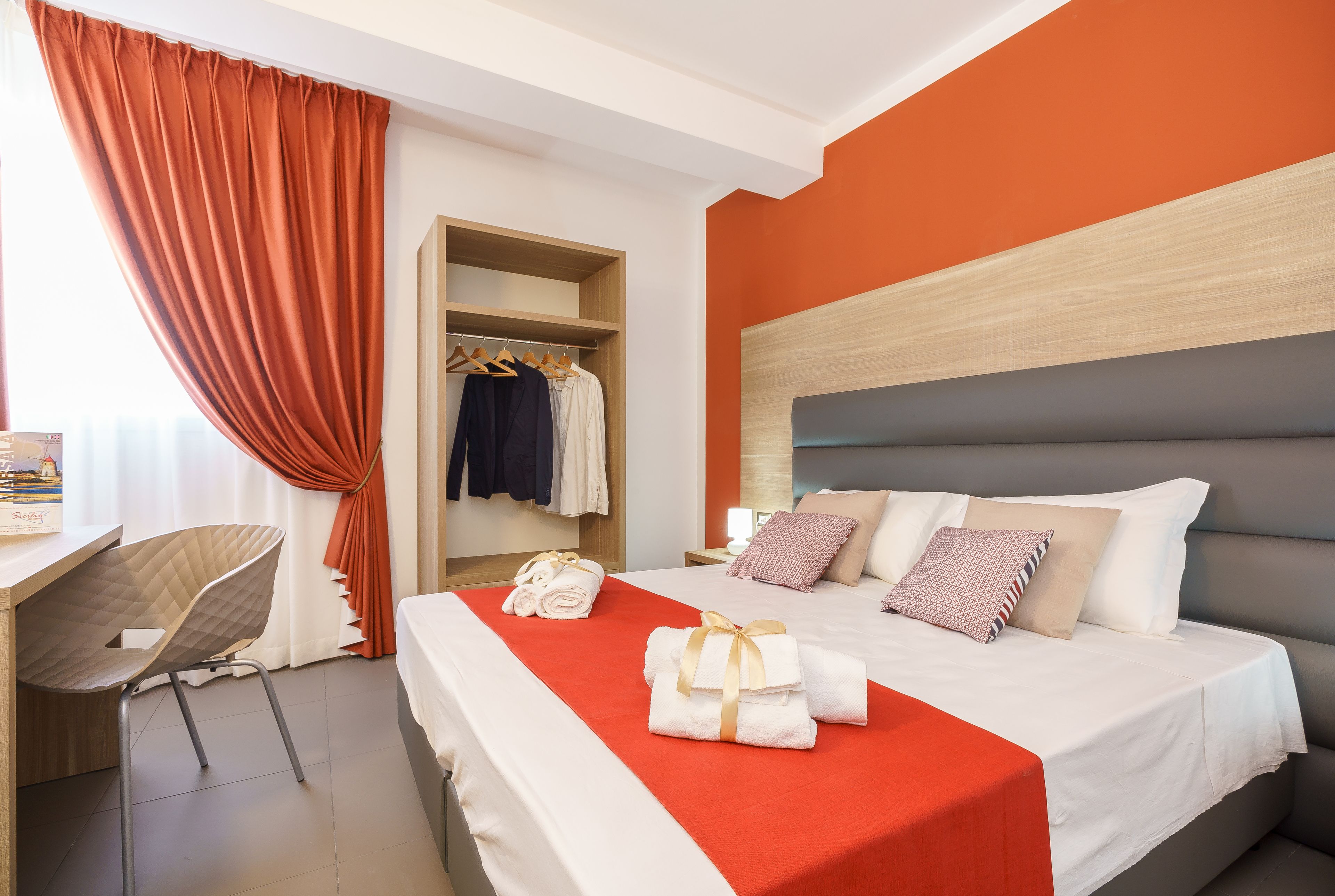 A hotel room with a bed, a desk, and a wardrobe.