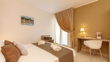 Una camera d'albergo con un letto, una scrivania, una sedia, una lampada e un quadro appeso al muro.