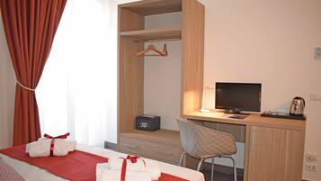 A hotel room with a bed, a desk, a chair, a TV, and a wardrobe.