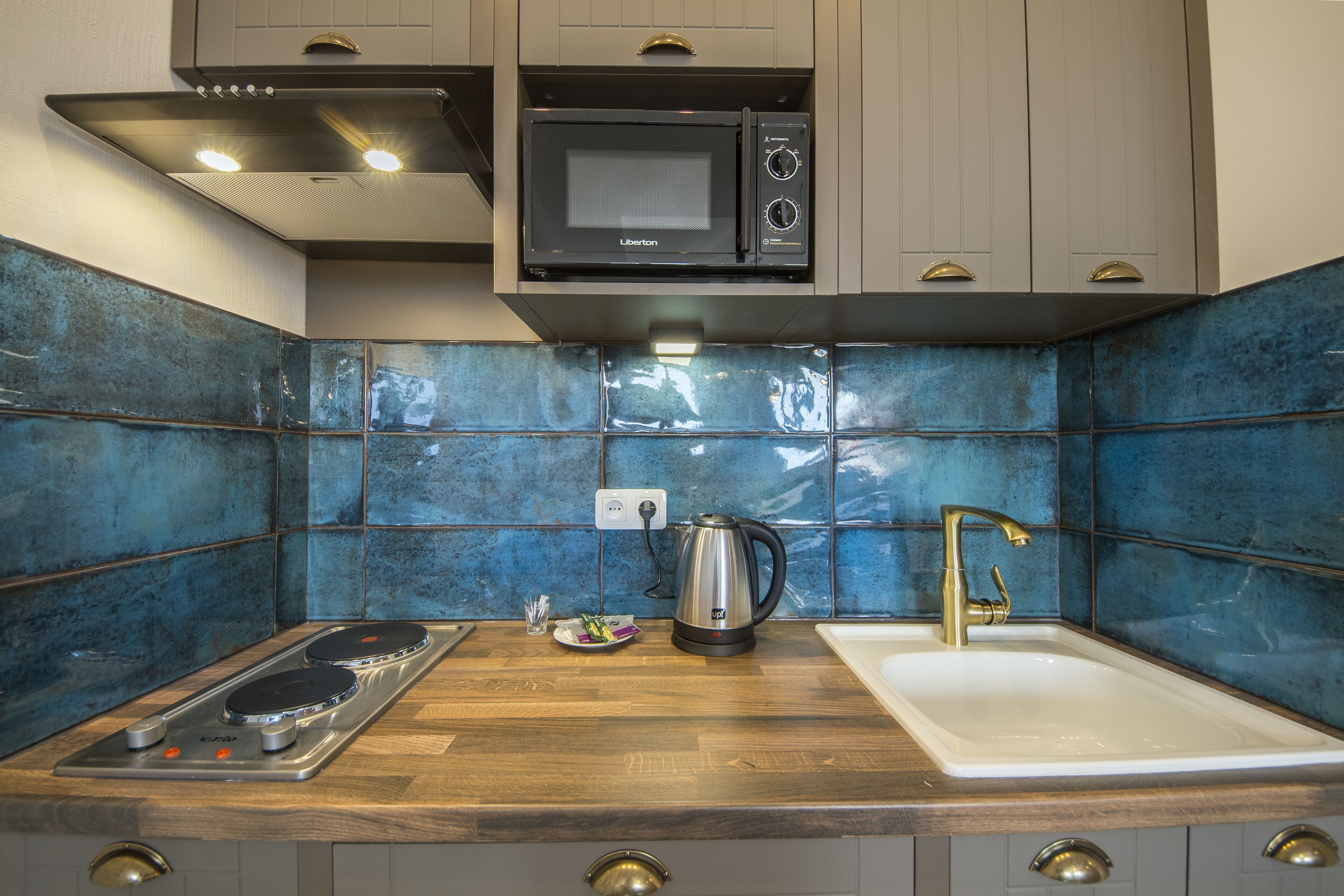A kitchen with a microwave, kettle, and sink.