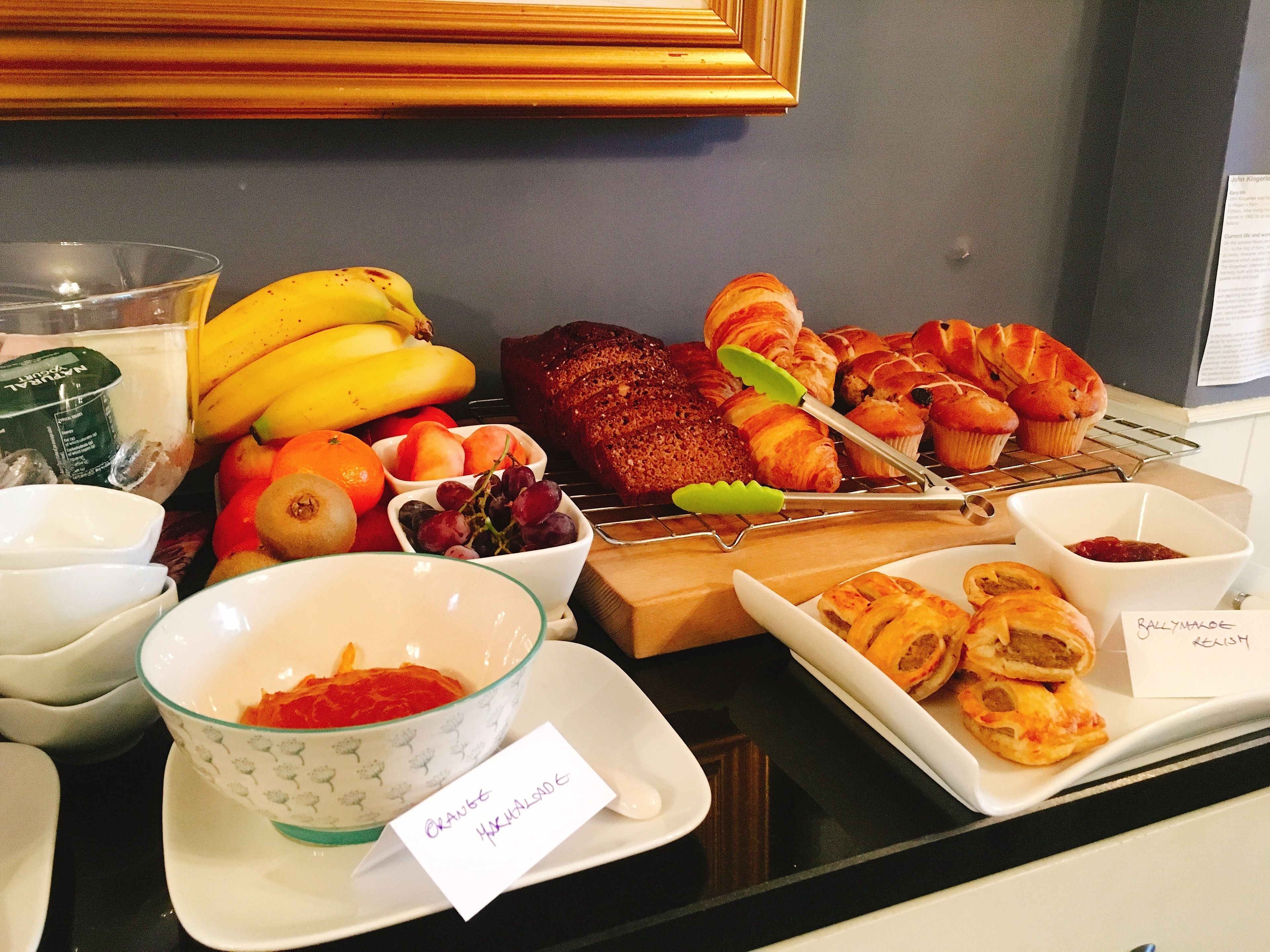 A breakfast buffet with various fruits, pastries, and bread.