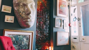 A room with a large abstract painting, a red chair, and a black dog. - Rose Lodge Guest House (Cork)