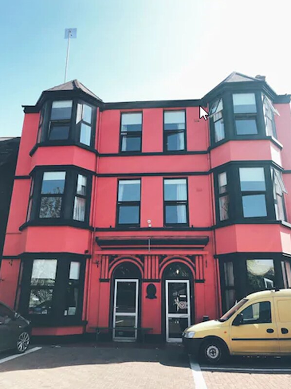 A red corner building with a black roof, a flag, and a yellow car parked in front.