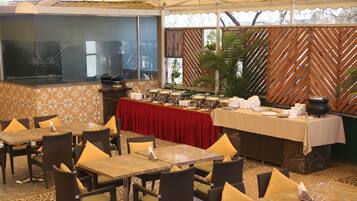 A restaurant with outdoor seating, a buffet table, and a decorative wooden partition.