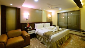 Una habitación de hotel con cama, sofá, mesita de noche y ventana con persianas.