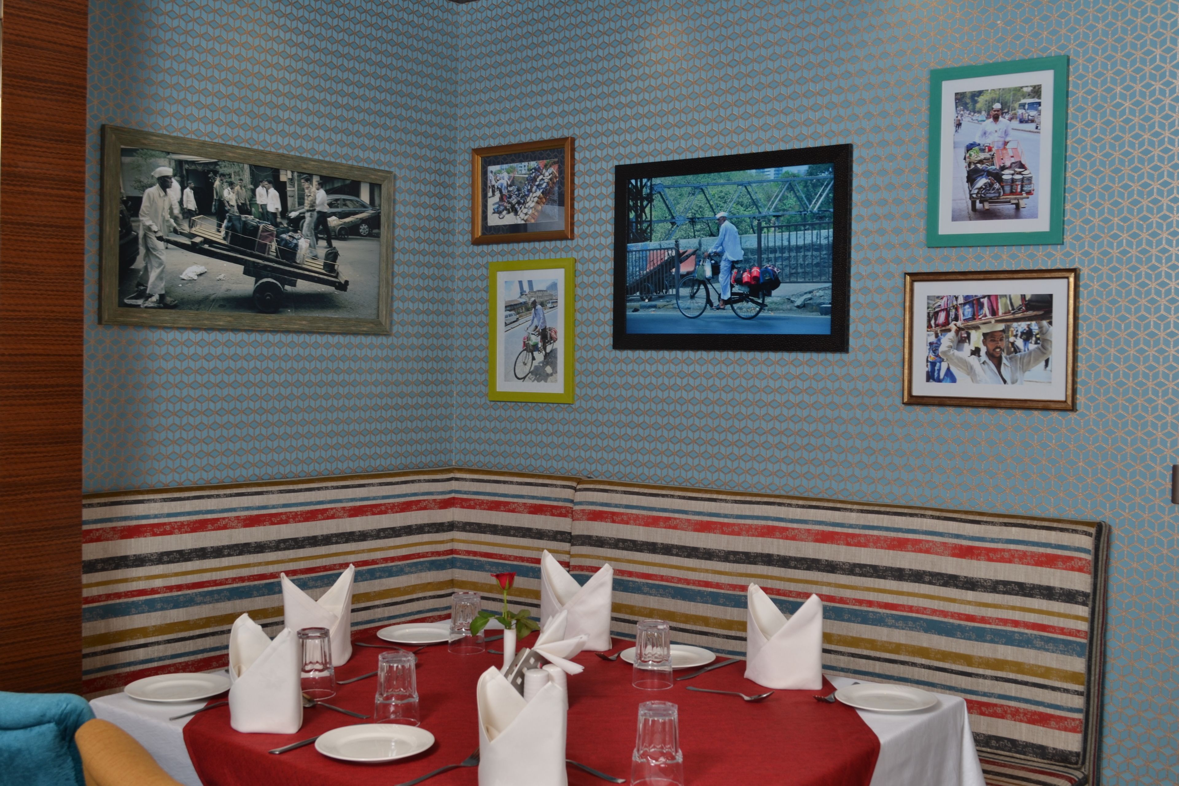 A dining area with striped booths, a red tablecloth, and framed pictures on the wall.