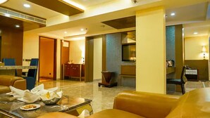 Un hall de hotel con asientos de cuero, una recepción y un comedor con una mesa de mármol.