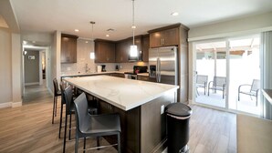 Una cocina moderna con una isla grande, electrodomésticos de acero inoxidable y una zona de comedor con taburetes de bar.
