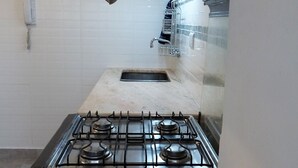 Eine Küche mit einem Gasherd, weißen Fliesenwänden und einer Holz Arbeitsplatte.