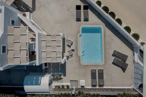 An aerial view of a hotel with a swimming pool, sun loungers, and a modern architectural design.