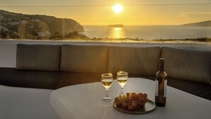 A table with two wine glasses, a bottle, and a plate of grapes.