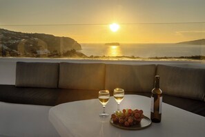 A table with two wine glasses, a bottle, and a plate of grapes.