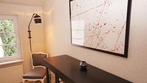 Une pièce comprenant un bureau, une chaise et un grand tableau abstrait accroché au mur.