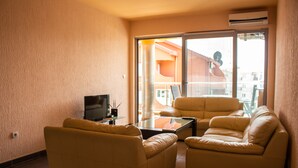 Appartement, uitzicht op stad | Woonruimte | Een 32-inch flatscreentelevisie met kabelzenders en een televisie