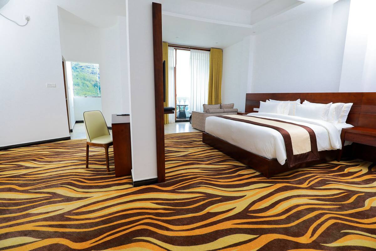 A hotel room with a large bed, a chair, a desk, and a view of a balcony.