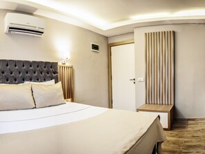 A hotel room with a large bed, an air conditioning unit, a bedside table with a lamp, and a wooden panel wall. - Sky Star Hotel (Bodrum)