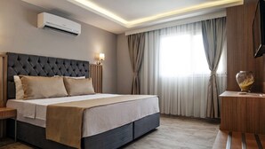 A modern hotel room with a large bed, a flat-screen TV, an air conditioning unit, and a wooden nightstand. - Sky Star Hotel (Bodrum)
