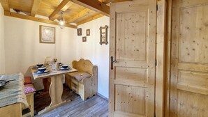 A wooden dining area with a table set for four, a bench, and a door with a traditional design. - 50m from resort center, 3rd floor, tv, ski locker, 22m², Saint Martin de Belleville (Saint-Martin-de-Belleville)