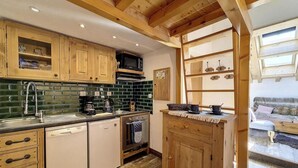 A compact kitchen with wooden cabinets, a dishwasher, a microwave, and a coffee maker. - 50m from resort center, 3rd floor, tv, ski locker, 22m², Saint Martin de Belleville (Saint-Martin-de-Belleville)