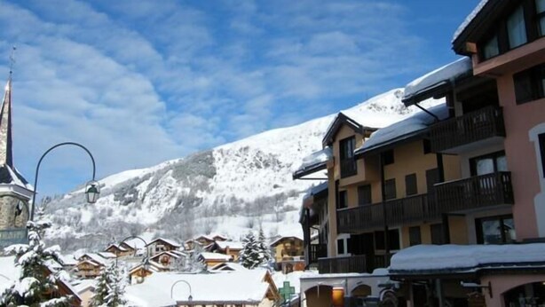 A snow-covered mountain town with traditional wooden buildings, a prominent clock tower, and a clear blue sky. - 50m from resort center, 3rd floor, tv, ski locker, 22m², Saint Martin de Belleville (Saint-Martin-de-Belleville)