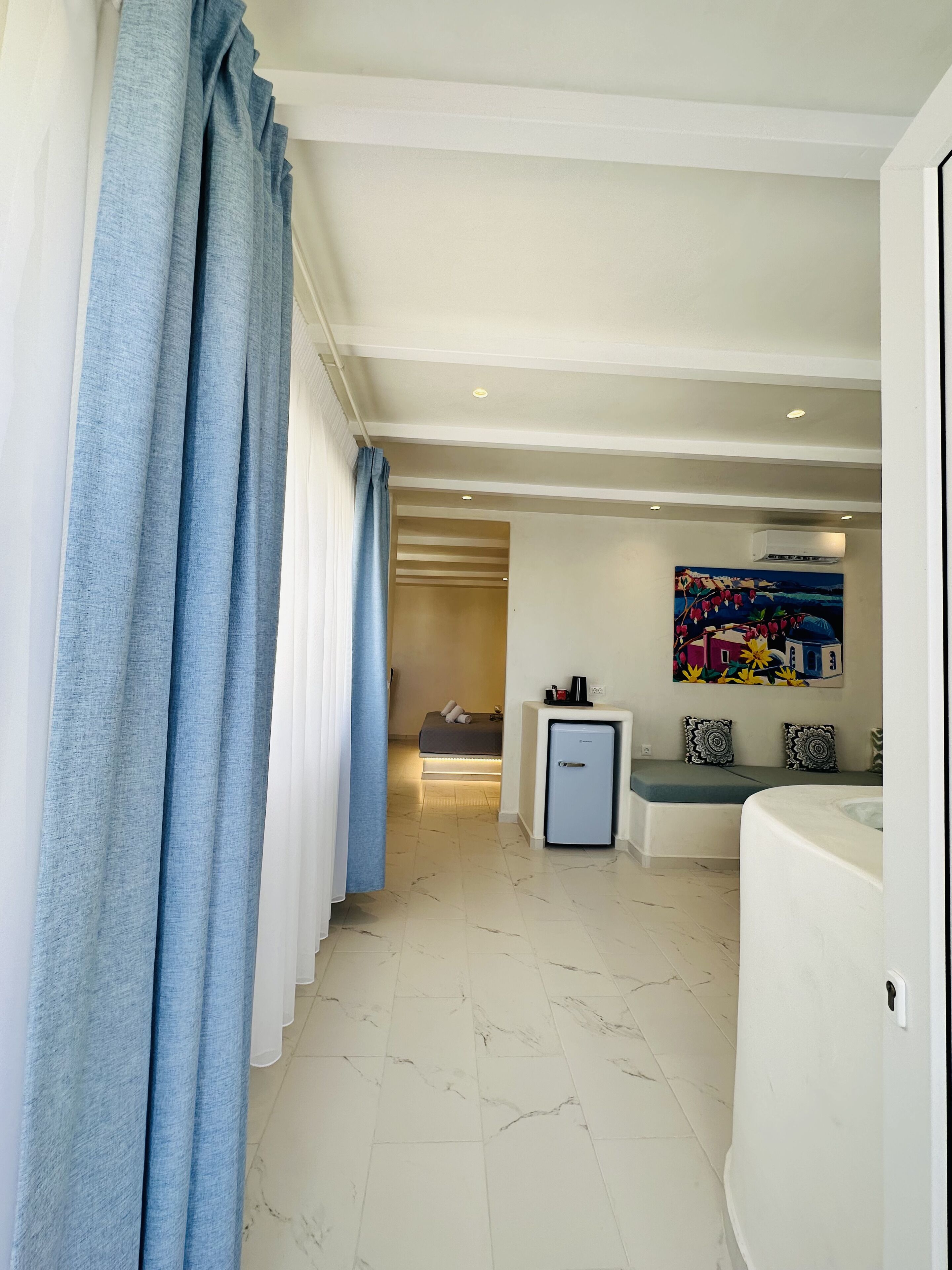 Une chambre d’hôtel avec un lit, un petit bureau, un réfrigérateur et un tableau au mur.
