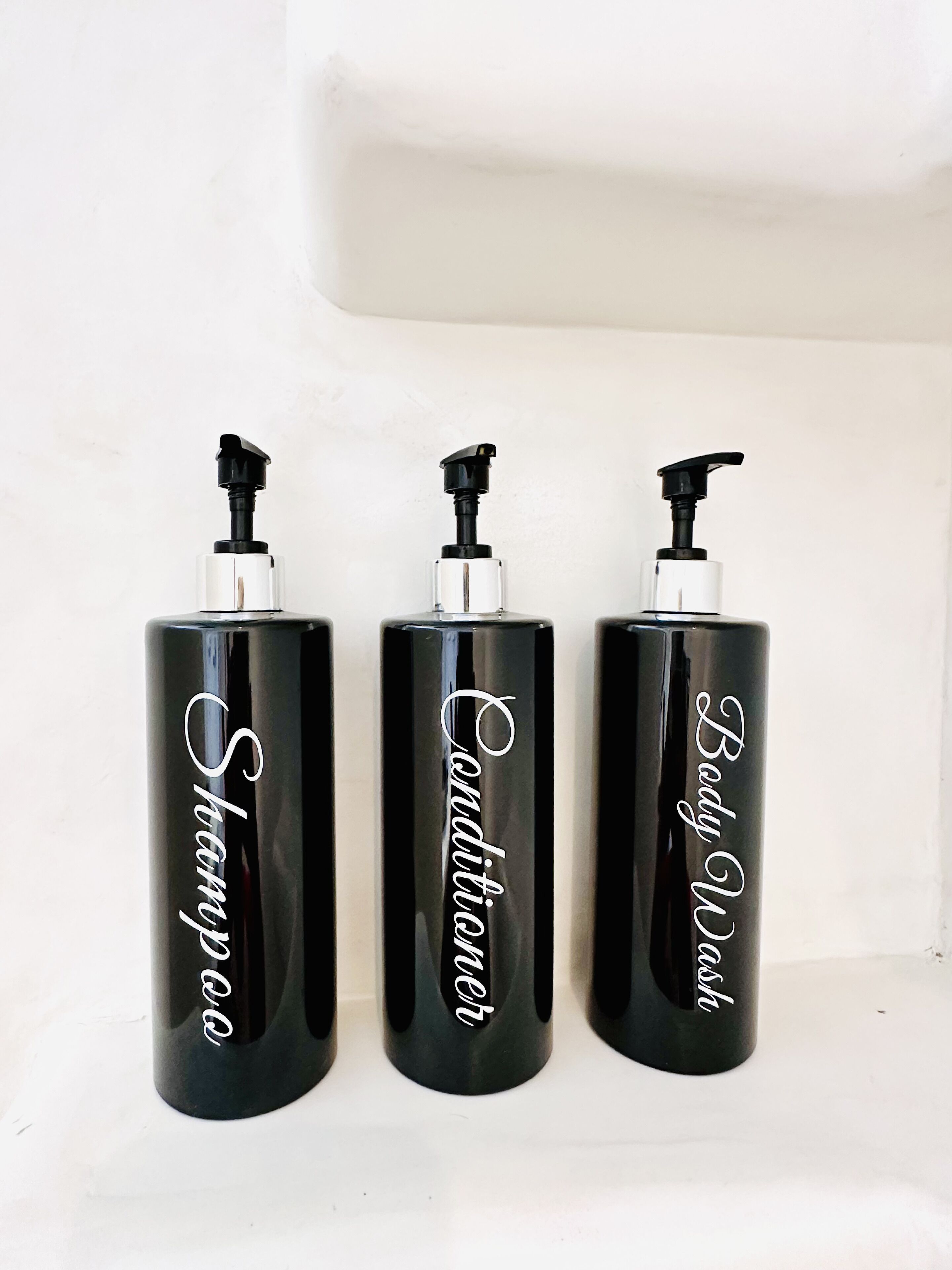 Three black bottles with pumps and white text against a white background.