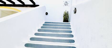 Una escalera blanca con escalones azules que conducen a una puerta.