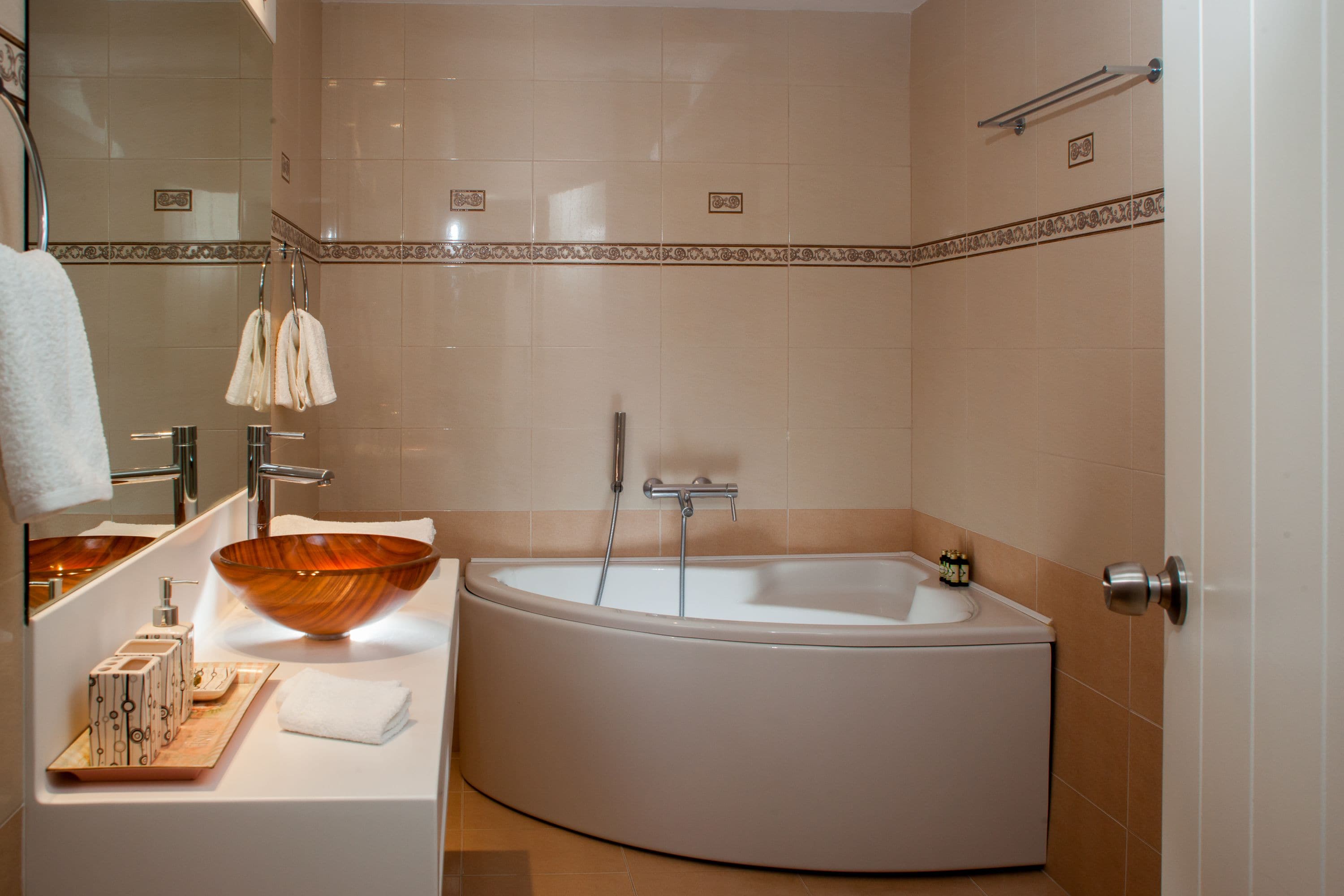Une salle de bain moderne avec une grande baignoire ovale, un lavabo en forme de bol en bois et un miroir au-dessus du lavabo.