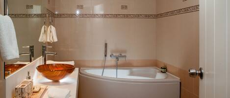 Une salle de bain moderne avec une grande baignoire ovale, un lavabo en forme de bol en bois et un miroir au-dessus du lavabo.