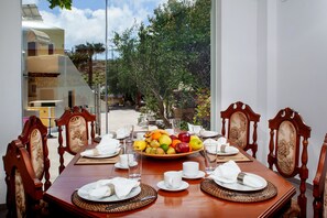 A dining table set for six with a fruit bowl, plates, cutlery, and glasses. - Arlene Suites (Santorini)
