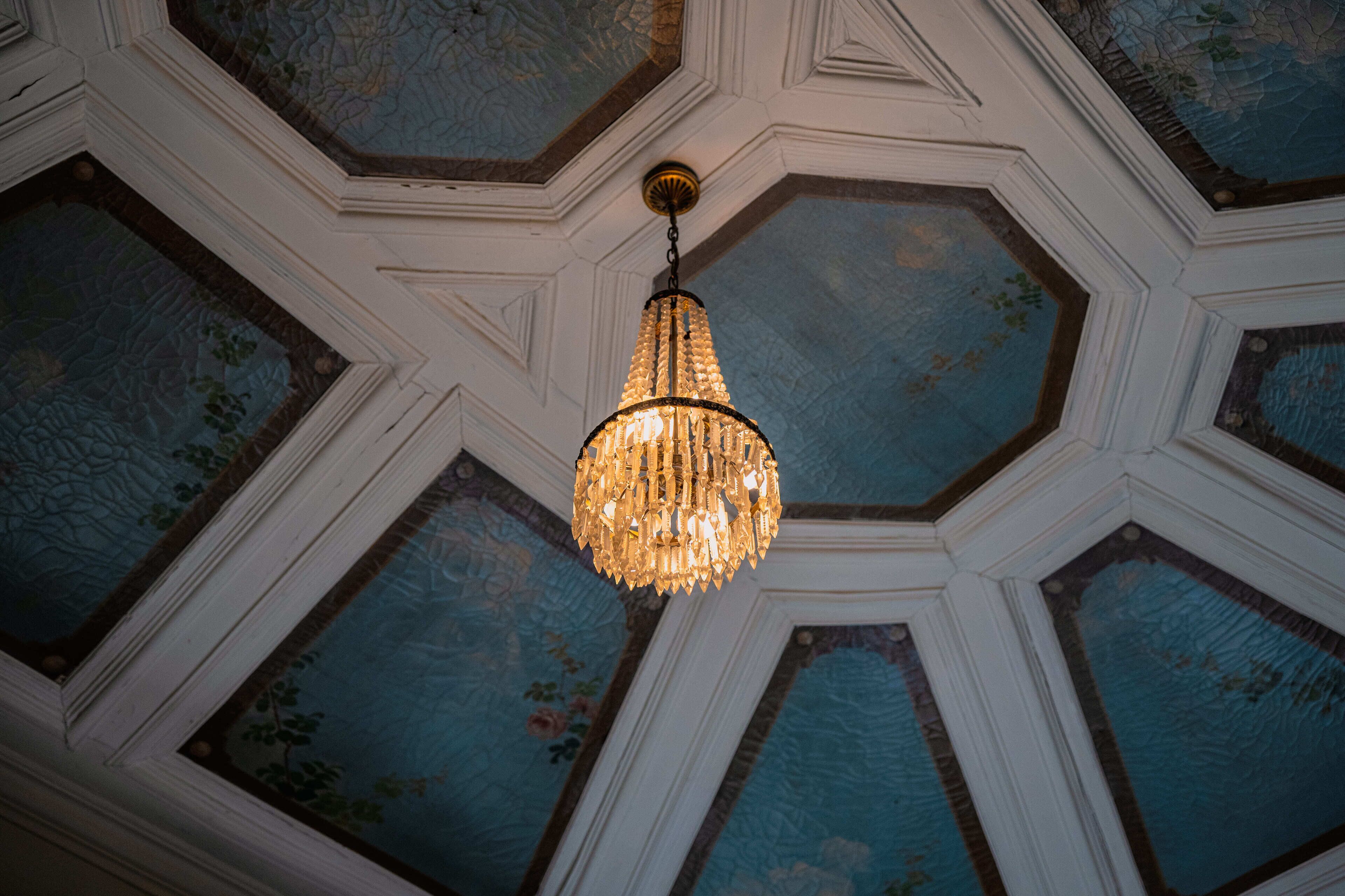 A chandelier hanging from a ceiling with geometric patterns and floral designs.