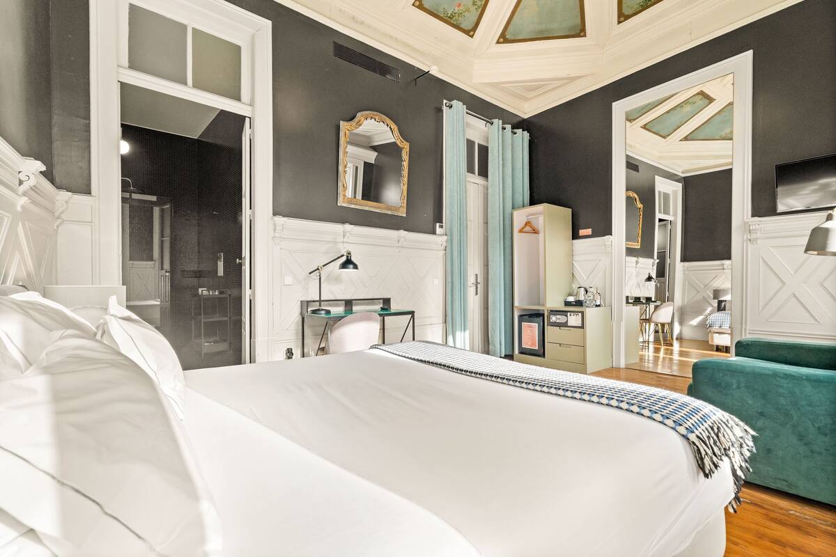 A bedroom with a large bed, a desk, a chair, and a TV.