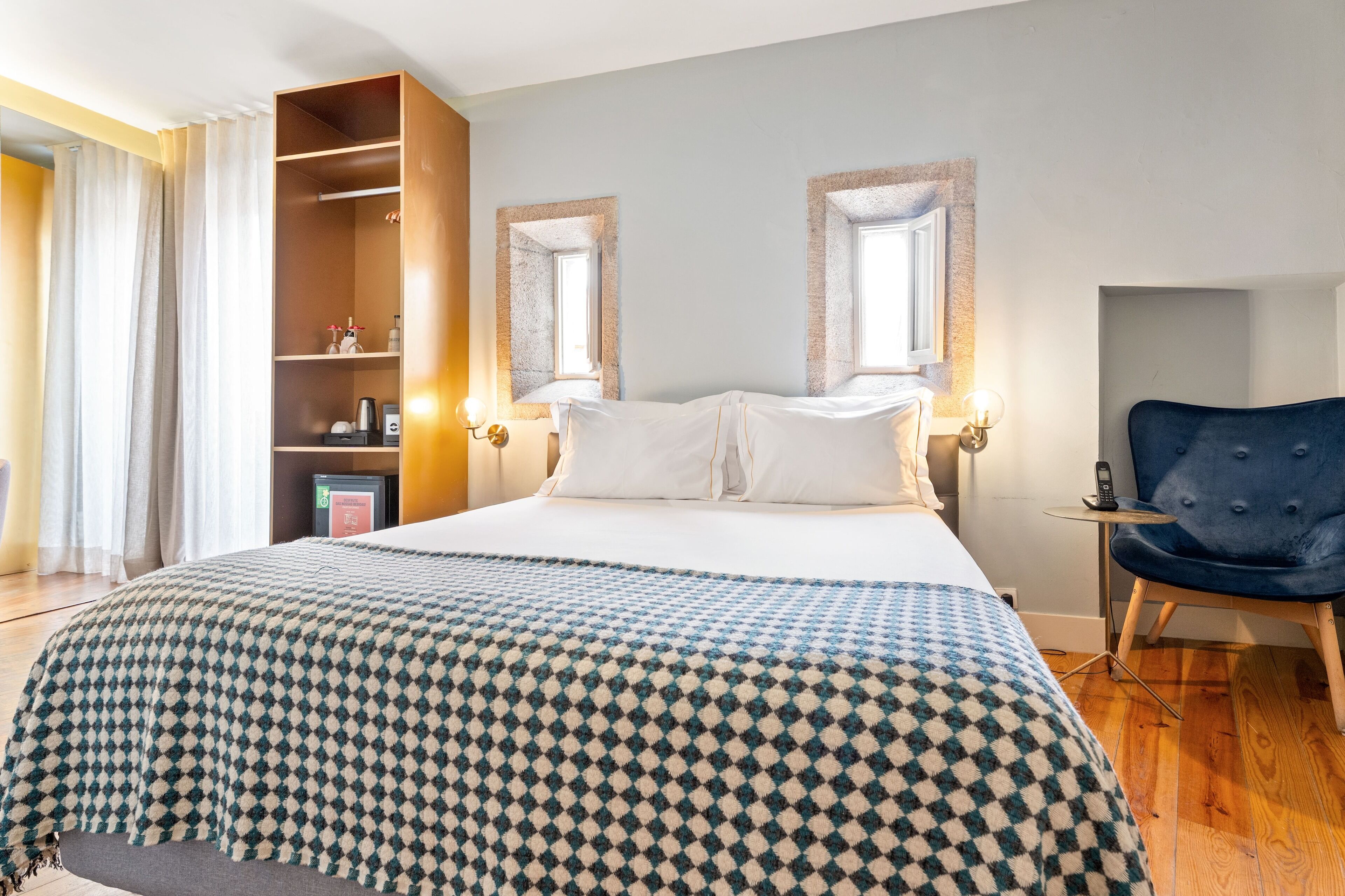 A hotel room with a large bed, two bedside tables, a wardrobe, and a chair.