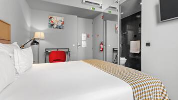 A hotel room with a bed, a red chair, a lamp, an air conditioning unit, and a shower area.